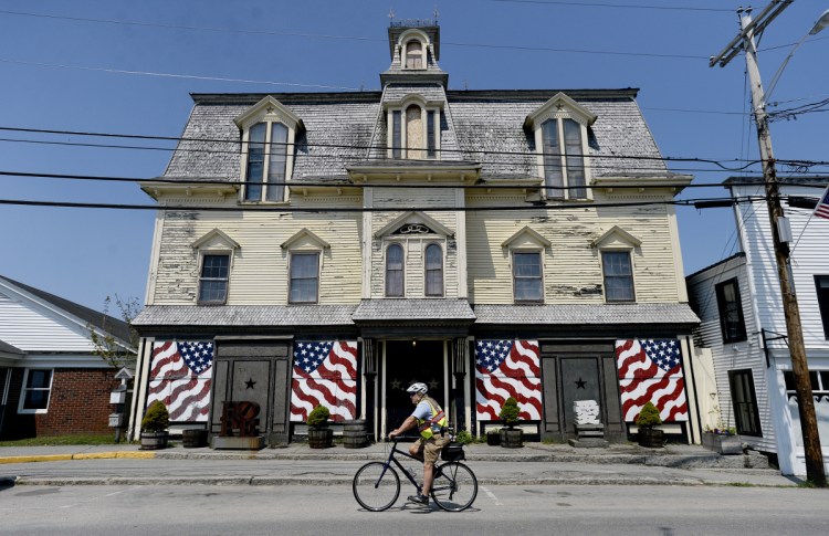 Vinalhaven resident Chuck Clapham rides past Robert Indiana's home on the Penobcot Bay island, a former Odd Fellows hall called Star of Hope. An attorney for Indiana will meet with others on Aug. 15 for a hearing on 28 pieces of art missing from the home. Those artworks are listed in exhibition catalogs as belonging to Indiana, but weren't found in Star of Hope. Staff photo by Shawn Patrick Ouellette