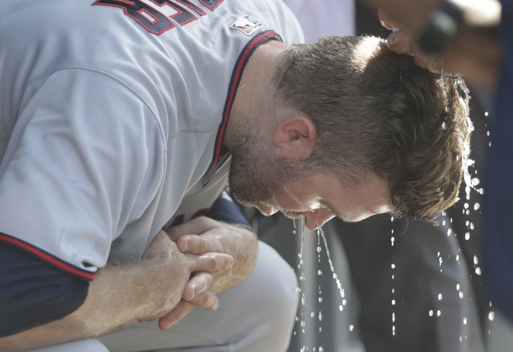 Minnesota's Brian Dozier has water from a cold wet towel squeezed onto his head during the seventh inning of the Twins' 14-9 loss to the Cubs on Saturday in Chicago. The Cubs said it reached 96 degrees with a heat index of 107.