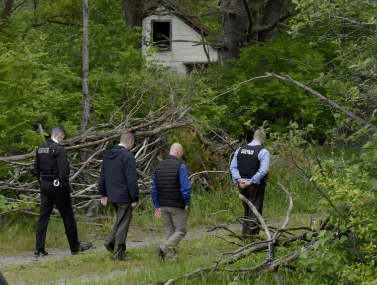 Maine State Police detectives walk toward the site on Tuesday where an excavator is digging for clues at an abandoned building, background, off Route 150 in Skowhegan, as police continue their investigation into the disappearance of Tina Stadig, who has been missing for more than a year.
