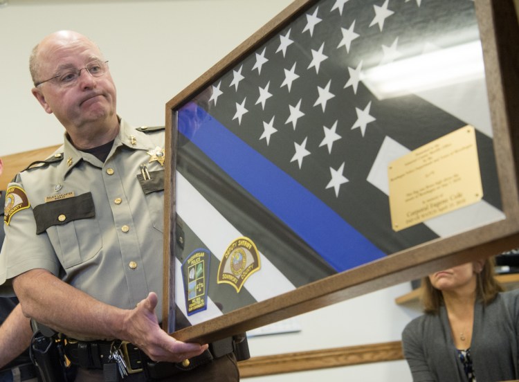 Somerset County Sheriff Dale Lancaster receives a memorial flag Tuesday in honor of the late Cpl. Eugene Cole, of the Somerset County Sheriff's Office, from Skowhegan police chief David Bucknam at the Skowhegan Municipal Building.
