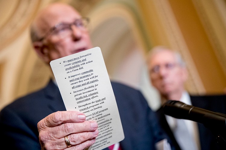 Sen. Pat Roberts, R-Kan., left, accompanied by Senate Majority Leader Mitch McConnell of Ky., right, reads from notes on the farm bill in Washington on Tuesday.
