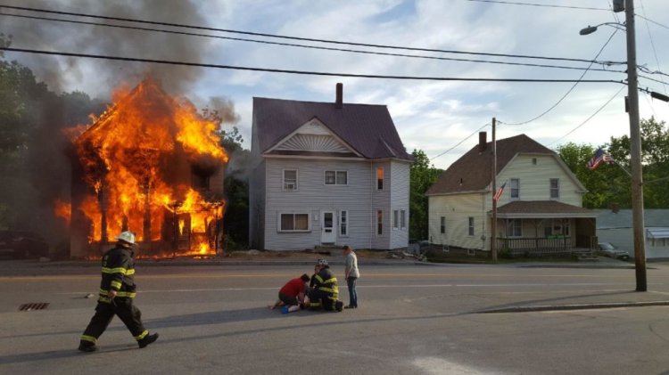 People tend to a child who escaped a burning house Tuesday night on Main Street/Route 4 in Livermore Falls. The child was injured when he jumped from a window, witness Warren Forbes of Livermore said. 