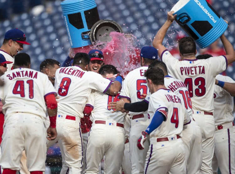 Andrew Knapp, center, is doused by his Phillies teammates at home plate after hitting a walkoff home run in the 13th inning against Washington on Sunday.