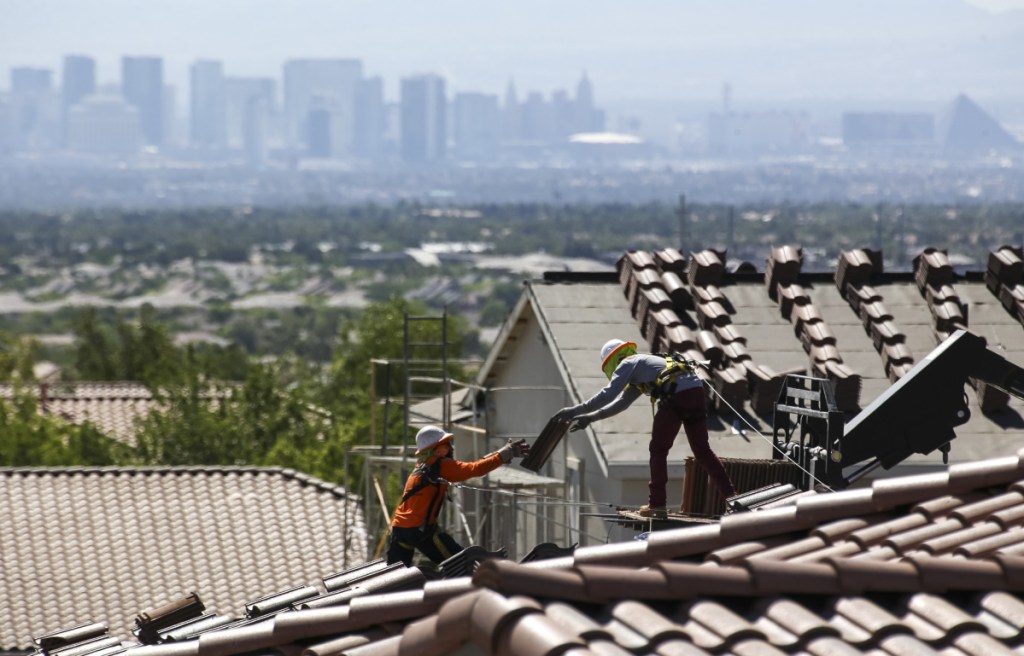 Construction workers set bundles of tile on the roof of an under-construction house in the master-planned community of Summerlin in Las Vegas. The Commerce Department reported Monday that U.S. construction spending rose in May.