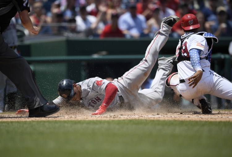 Boston's Rafael Devers, left, slides home past Washington catcher Pedro Severino to score on a sacrifice fly by Jackie Bradley Jr., during the seventh inning Wednesday's game in Washington.