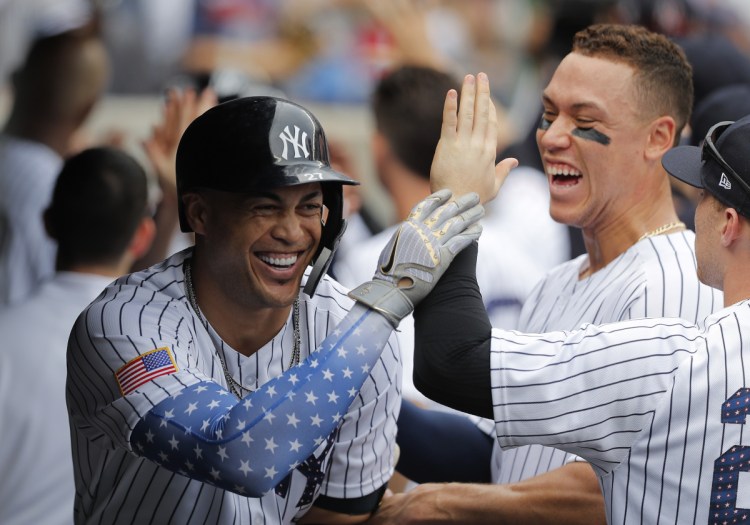 Giancarlo Stanton, left, celebrates in the dugout after smacking a three-run homer in the third inning Wednesday at Yankee Stadium. The Yankees added two more home runs in the game to beat the Braves, 6-2.