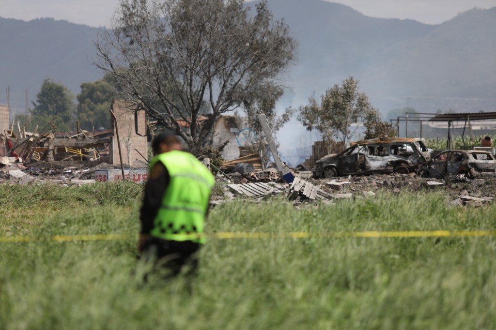 A series of four explosions destroyed four fireworks workshops in Tultepec, Mexico, on Thursday. Officials say the blasts were triggered by an explosion at an unauthorized operation that shot flammable material into the air and set off the subsequent locations.
A police officer guards the perimeter around the wreckage of several fireworks workshops in Tultepec, Mexico, Thursday, July 5, 2018. More than a dozen people were killed and at least 40 injured  when a series of explosions ripped through fireworks workshops in a town just north of Mexico City. (Associated Press/Emilio Espejel)
