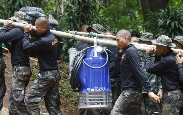 Soldiers carry a pump to help drain the rising flood water Friday in a cave where 12 boys and their soccer coach have been trapped since June 23, in Mae Sai, Chiang Rai province, in northern Thailand.