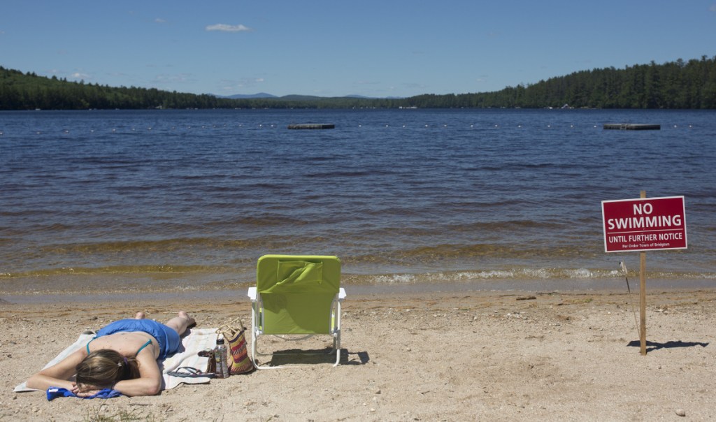 Christy Dow of Naples sunbathes on July 7 at Woods Pond Beach in Bridgton, where a number of people reported falling ill after being in the water.