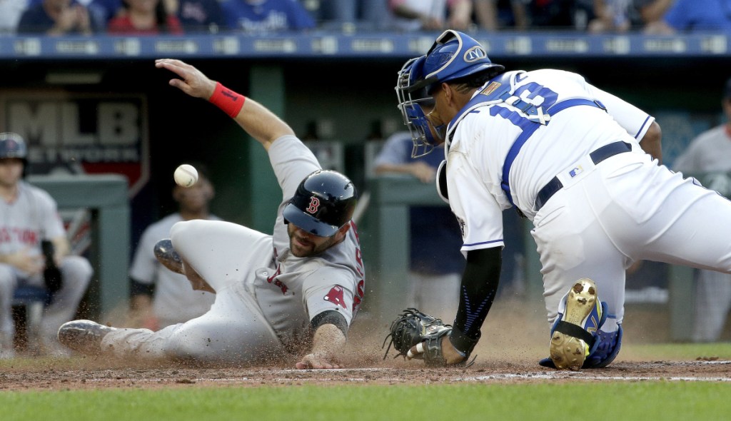 Mitch Moreland of the Red Sox beats a tag by Kansas City catcher Salvador Perez to score on a three-run double by Xander Bogaerts in the fifth inning of Boston's 15-4 win Saturday night.