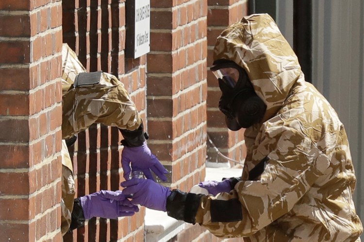 Police specialist team members in protective suits search the front doorway of the fenced-off John Baker House for homeless people in Salisbury, England, on Friday. 