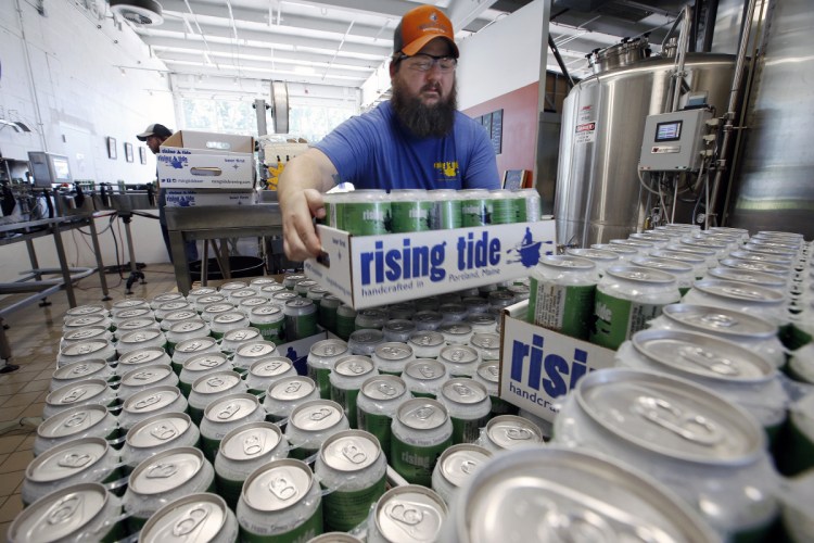Merritt Waldron stacks cases of the popular seasonal beer MITA. Breweries such as Rising Tide, which made 243 percent more beer in July than in February last year, have learned that cashing in on summer is the key to surviving the lean winter months. 