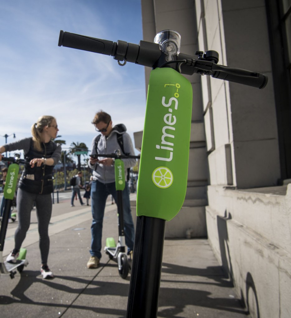 People use a smartphone to LimeBike shared electric scooters in San Francisco.