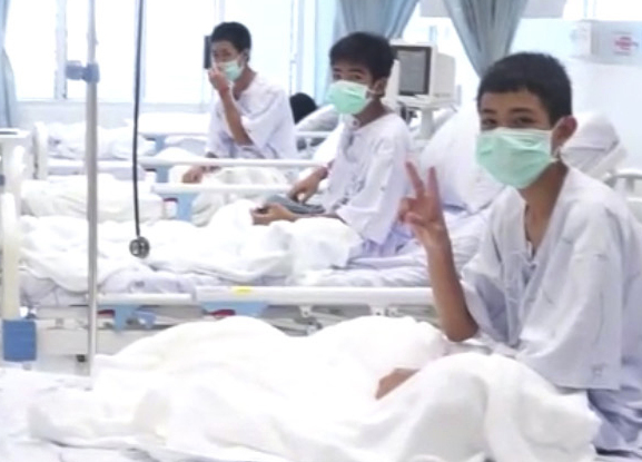 A video image shows three of the 12 rescued boys recovering in their hospital beds in Chiang Rai. Their parents have been allowed to see – but not touch – them.