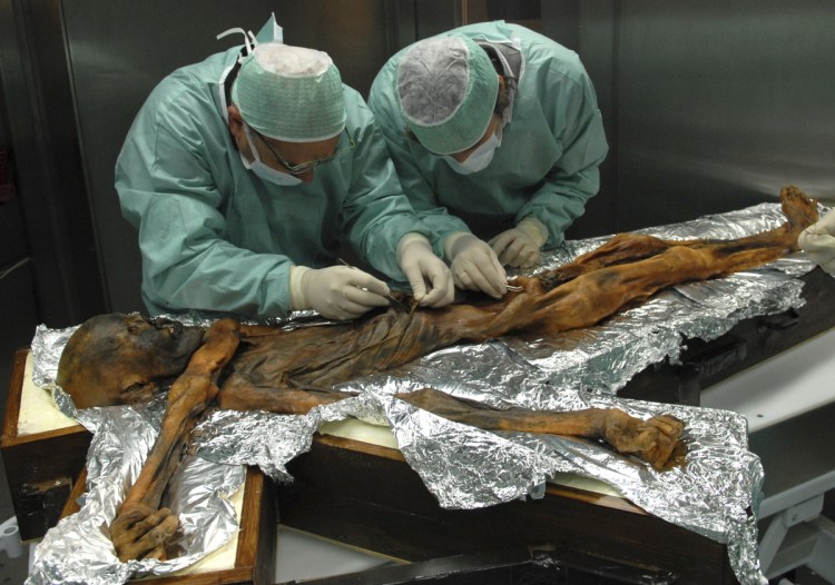 Researchers examine the body of a frozen hunter known as Oetzi the Iceman to sample his stomach contents in Bolzano, Italy in 2010.