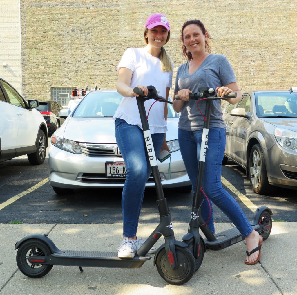 Kirby Bridges, left, and Megan Garlington pose with the Bird scooters they were taking for a ride in Milwaukee. Milwaukee is suing California-based Bird to stop the company from renting bikes because the city contends they are illegal to operate on streets and sidewalks.
