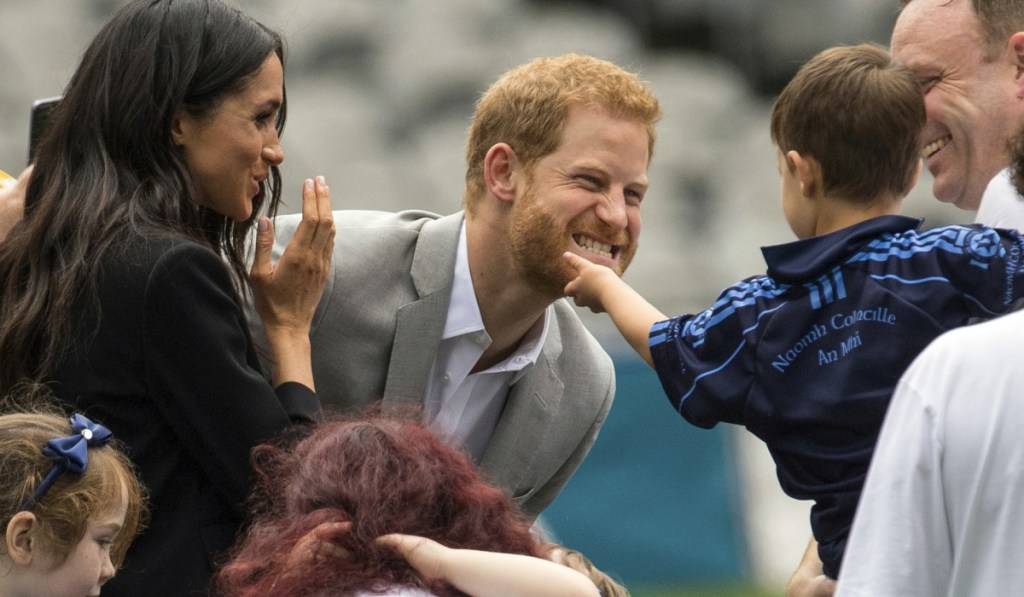 A boy strokes Prince Harry's beard as Meghan, the Duchess of Sussex, smiles in Dublin, Ireland, Wednesday.