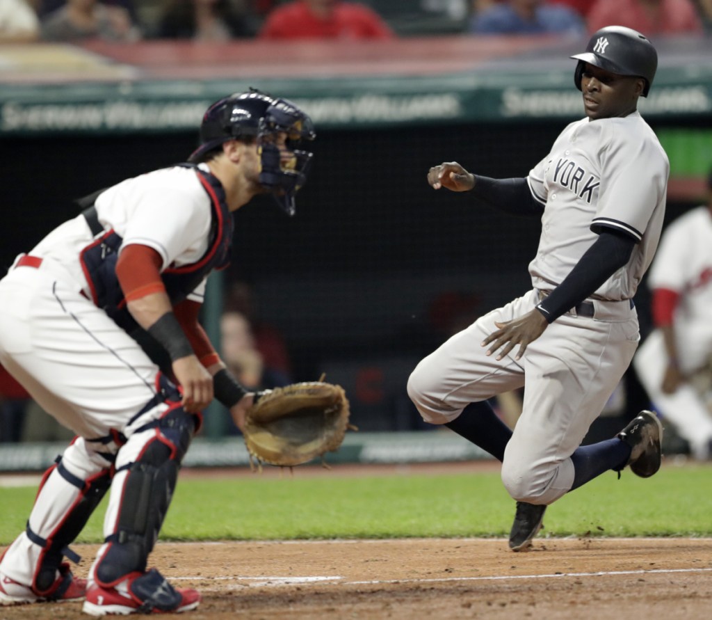 Didi Gregorius of the Yankees scores the go-ahead run on a double by Aaron Hicks as Indians catcher Yan Gomes waits for the throw during the eighth inning Thursday in Cleveland. New York went on to a 7-4 victory.