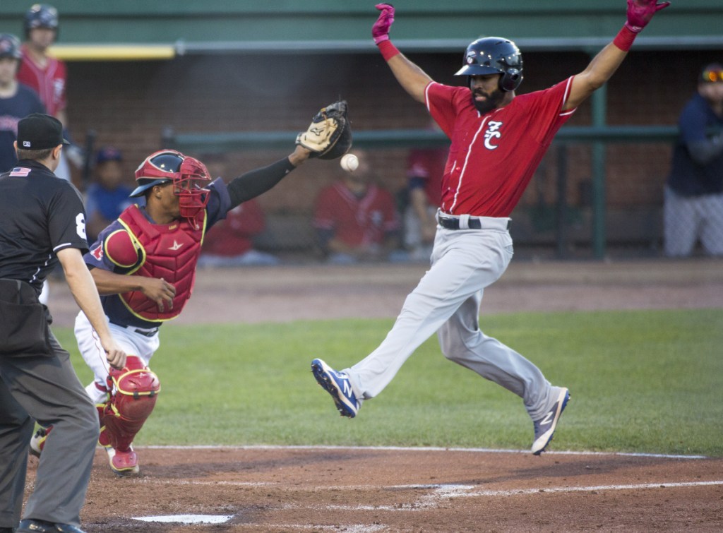 Catcher Jhon Nunez of the Portland Sea Dogs attempts to hold the ball as Dalton Pompey of the New Hampshire Fisher Cats prepares to score Friday night during the fourth inning of New Hampshire's 5-3 victory at Hadlock Field.