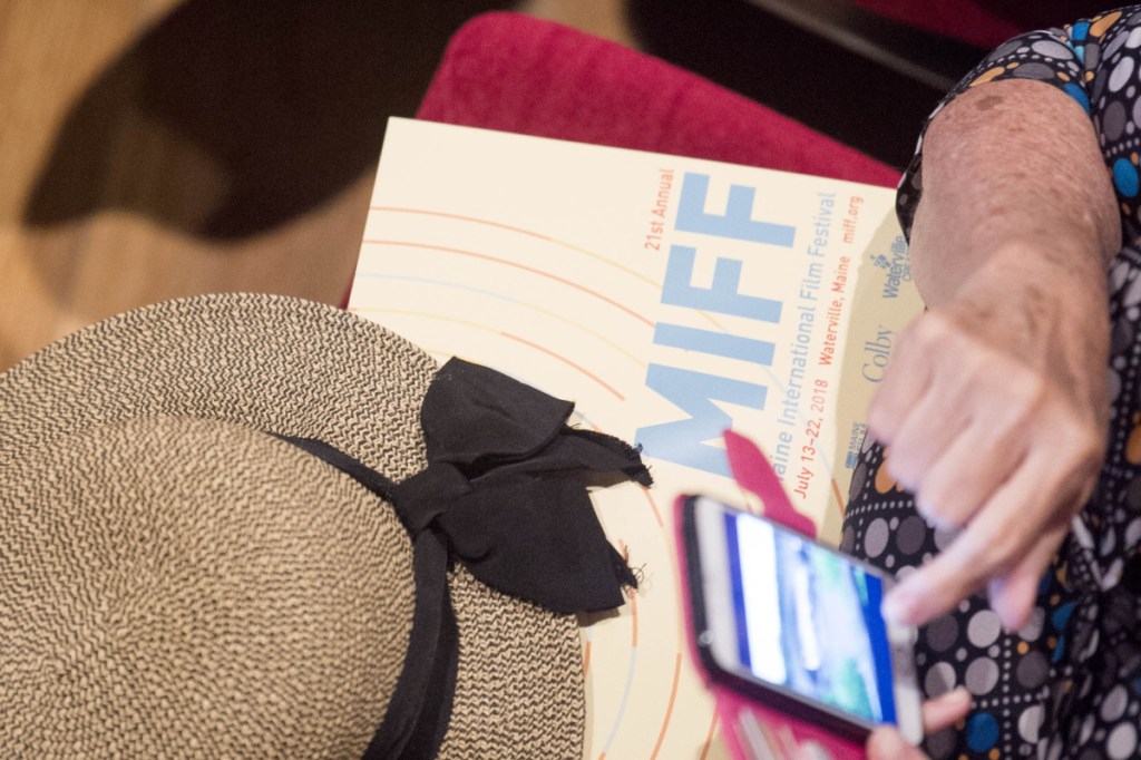 A filmgoer browses her phone Friday as she sits with a program at the Maine International Film Festival in Waterville. MIFF kicked off Friday night with a showing of "The Bookshop."