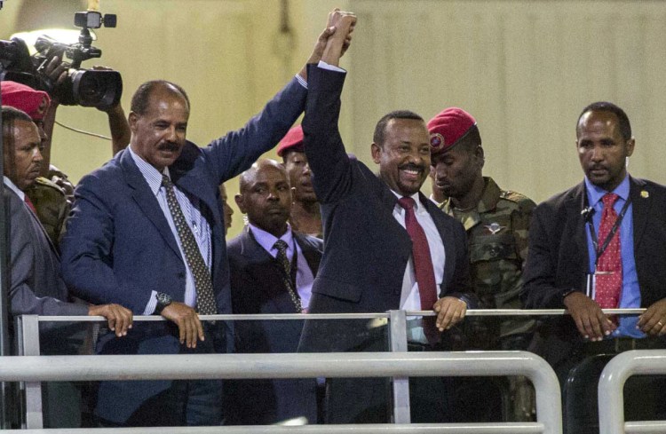 Eritrean President Isaias Afwerki, second left, and Ethiopia's Prime Minister Abiy Ahmed, center, hold hands as they wave at the crowds in Addis Ababa, Ethiopia, on Sunday.