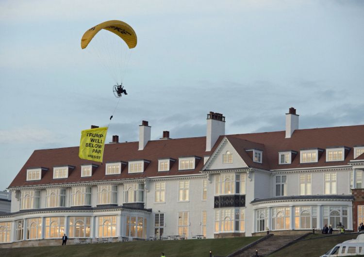 A Greenpeace protester flies a microlight over President Trump's resort in Turnberry, South Ayrshire, Scotland, with a banner reading "Trump: Well Below Par."