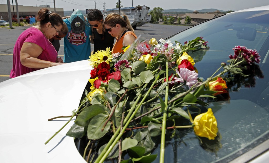 People pray next to a car believed to belong to a victim of Thursday night's duck boat accident in the country-and-western tourist town of Branson, Mo.