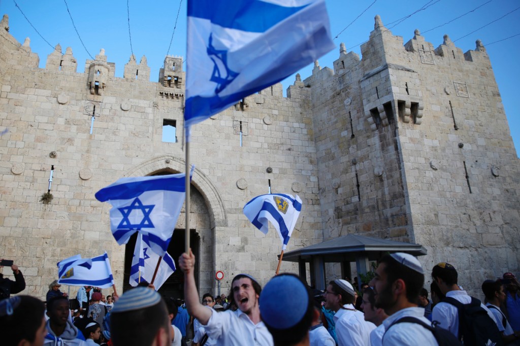 Israelis wave national flags outside the Old City's Damascus Gate, in Jerusalem, in May. A new law that defines Israel as the nation-state of the Jewish people will sideline minorities such as the country's Arabs.