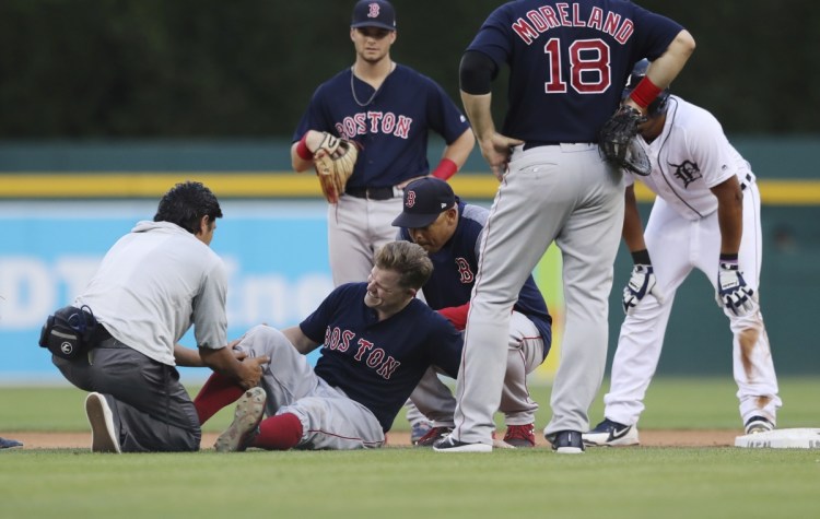 Boston second baseman Brock Holt is examined after colliding with Detroit's Jeimer Candelario in the fourth inning Friday night in Detroit. Holt had to leave the game with a knee contusion.