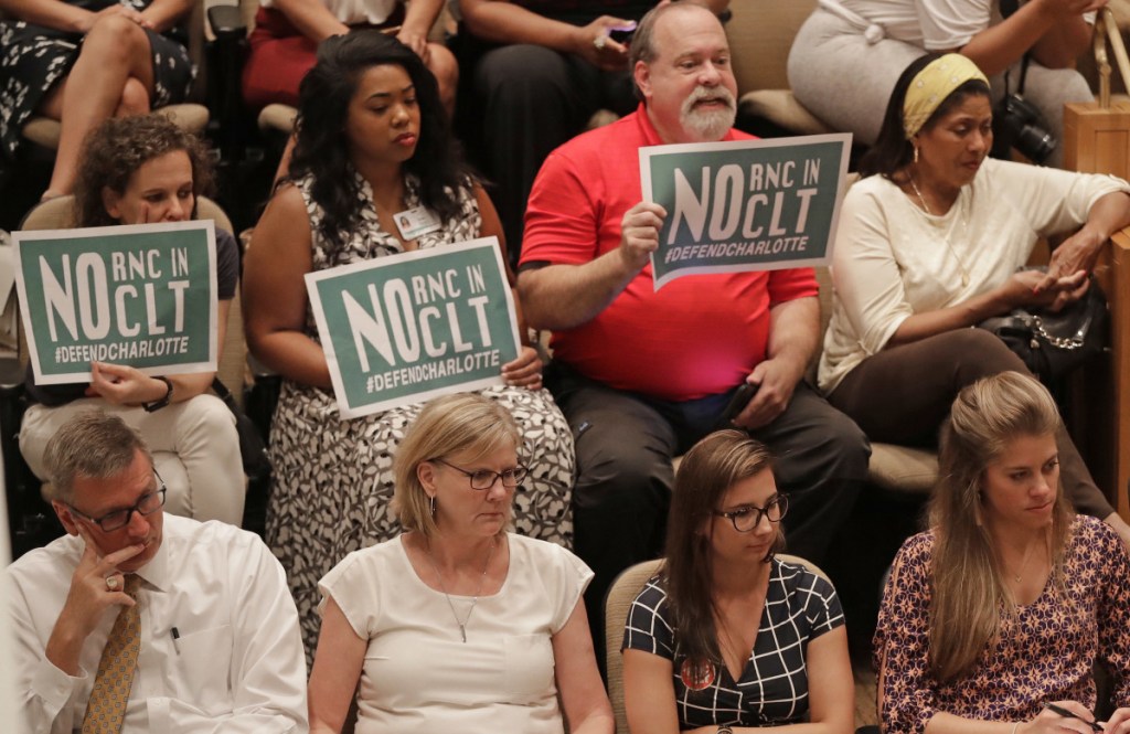 People hold signs for and against Charlotte, N.C., hosting the 2020 Republican National Convention during a public forum. The city has long been considered the front-runner.