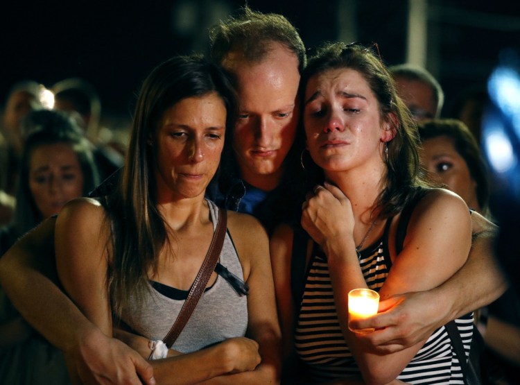 Mallory Cunningham, left, Santino Tomasetti, center, and Aubrey Reece attend a candlelight vigil in the parking lot of Ride the Ducks on Friday, in Branson, Mo.