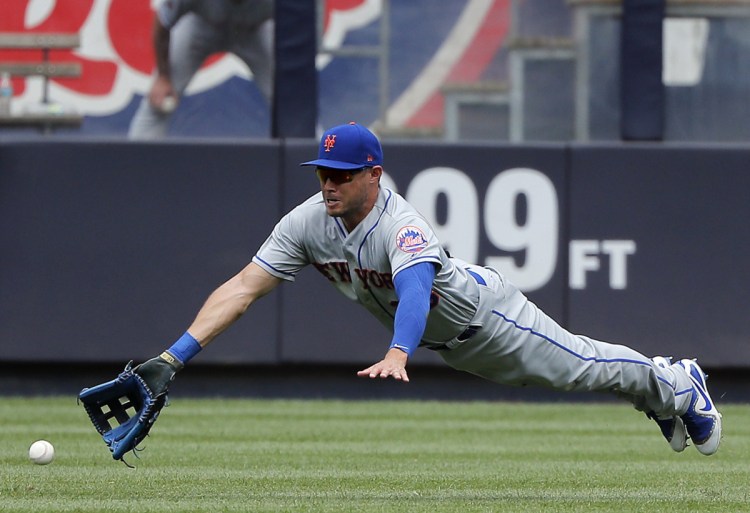 Mets center fielder Matt den Dekker dives but can't make the catch on an RBI single by Austin Romine of the Yankees in the fourth inning Saturday at Yankee Stadium in New York. The Yankees beat the Mets 7-6.