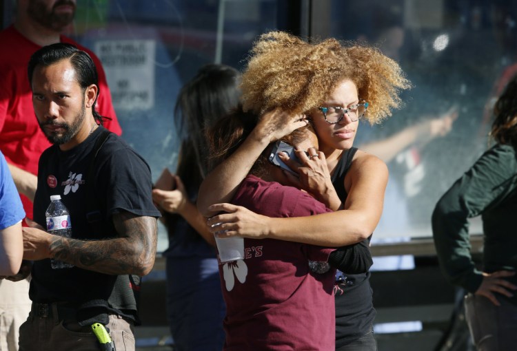 Unidentified Trader Joe's employees hug after Saturday's standoff, which ended when the gunman handcuffed himself and surrendered. Gene Evin Atkins faces a murder charge.