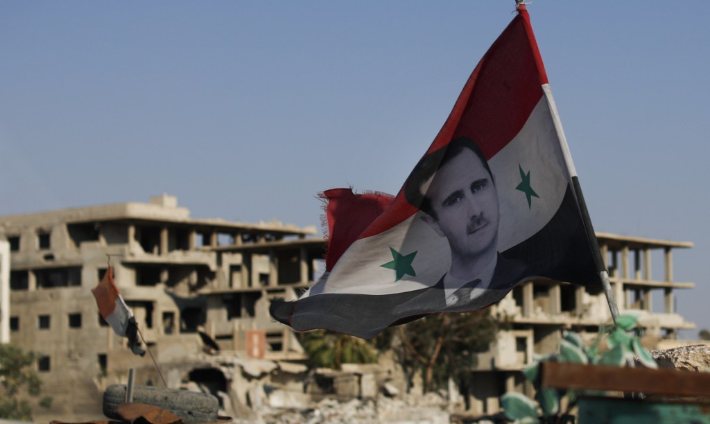 A Syrian flag with the picture of President Bashar Assad hangs at an Army checkpoint in Douma, Syria, on Sunday. Rescue workers known as the White Helmets, considered terrorists by Syria and Russia, were trapped near the Israeli border.