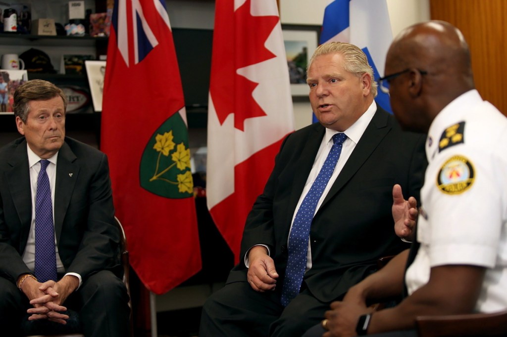 Toronto mayor John Tory, left, and Police Chief Mark Saunders, right, look on as Ontario Premier Doug Ford speaks during an intergovernmental meeting at Toronto City Hall on Monday in the wake of a mass shooting which happened in Toronto on Sunday night.