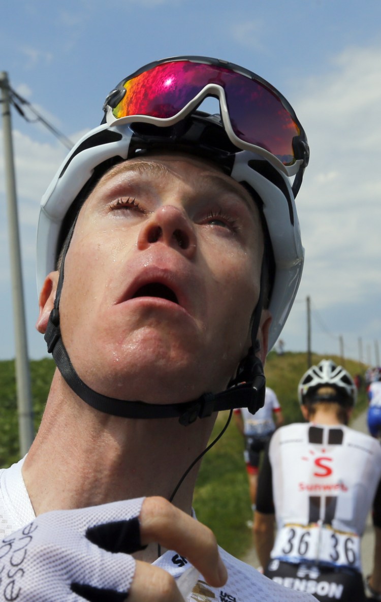 Chris Froome grimaces after treating his eyes for tear gas, which police used to disperse a farmers' protest that included bales of hay in the road Tuesday during the Tour de France.