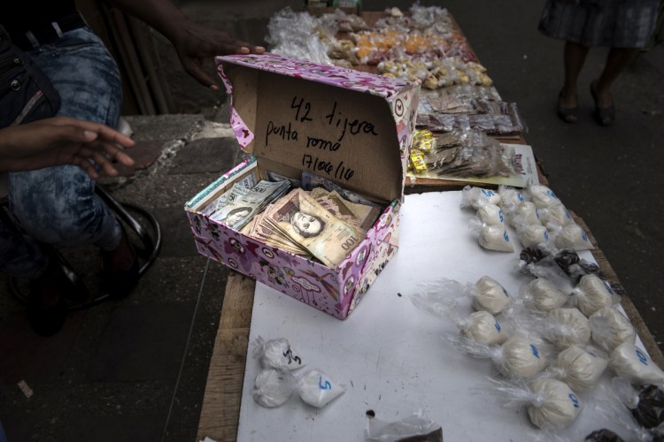 A street vendor opens a box of Bolivar banknotes at a stand in the Petare slum of Caracas, Venezuela. The country's economy has been broken by corruption, failed socialist policies and a collapsing oil industry.