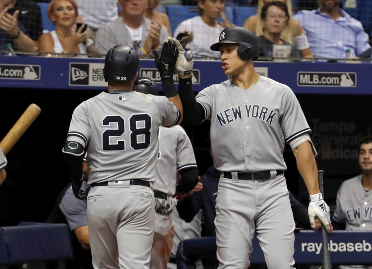 Austin Romine of the New York Yankees, left, is welcomed by Aaron Judge after hitting a sacrifice fly Tuesday night in the seventh inning of a 4-0 win over the Tampa Bay Rays