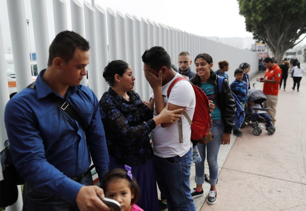 Calet Garcia, center, of Honduras, cries once he realizes he will be able to apply for asylum in the U.S. with his friend Daisy Avelar, second from left, of El Salvador, on Thursday near the San Ysidro port of entry in Tijuana, Mexico.