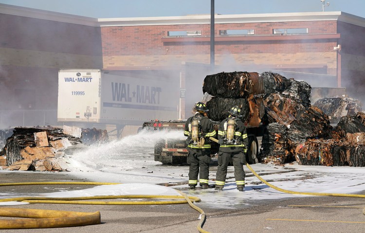 Scarborough firefighters spray foam on a pile of cardboard behind the Walmart in Scarborough on Thursday. Smoke from the fire entered the store, causing it to be evacuated. 