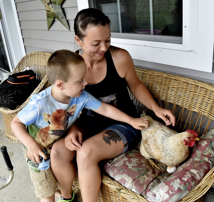 Athens farmer Kassie Dwyer and her son, Joey, try to coax a hen named Stumps off a porch couch Tuesday to see how many eggs she is sitting on at the Eden farm in Athens. Dwyer is launching an effort to enact an Athens Food Sovereignty Ordinance, which would allow consumers to buy directly from local farmers and food producers without state and federal licensing and inspections.