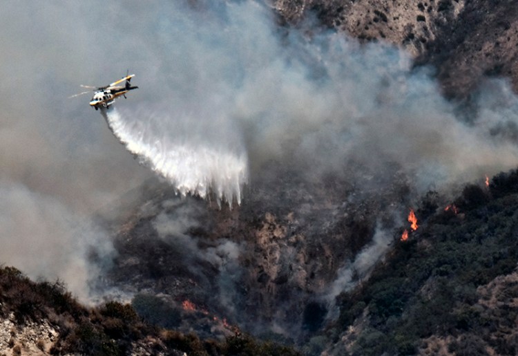 A Los Angeles County Fire Department helicopter drops water on a brush fire that erupted on a mountainside above suburban Burbank, Calif. on Saturday.