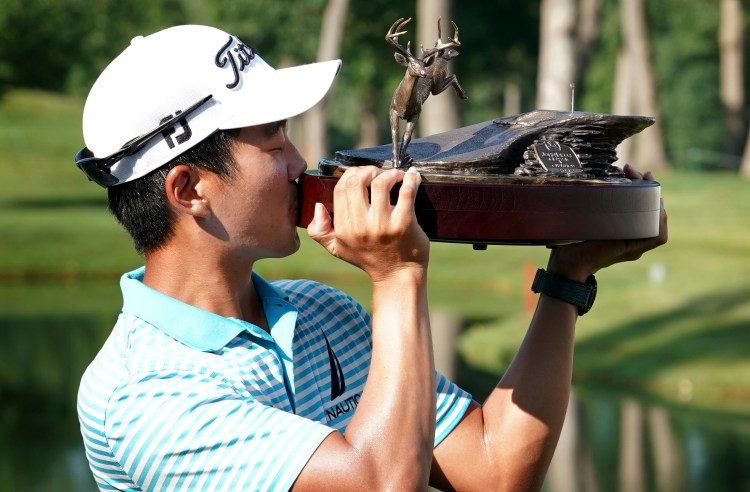 Michael Kim kisses the trophy after winning the John Deere Classic on Sunday at TPC Deere Run in Silvis, Ill. 