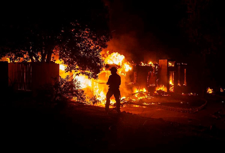A firefighter works to battle the Carr Fire at a home in Redding, Calif. on Thursday, July 26, 2018.