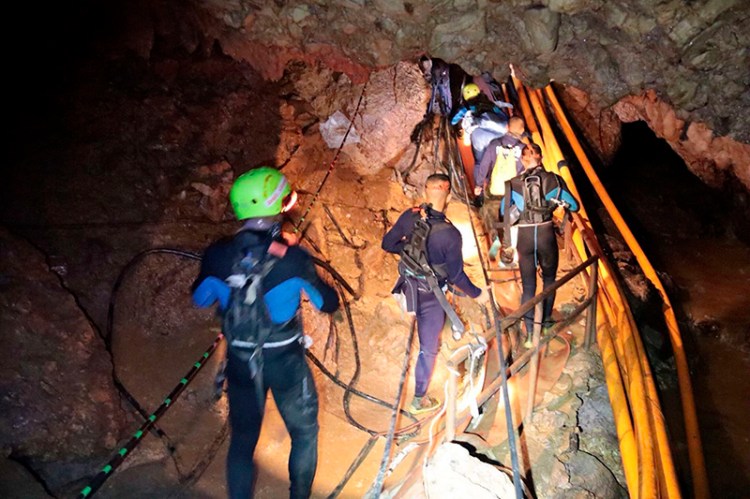 In this photo released by Royal Thai Navy on Saturday,  Thai rescue team members walk inside a cave where 12 boys and their soccer coach have been trapped since June 23.
