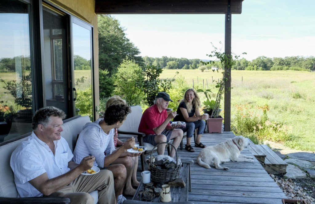 Matthew Grove, left, and his wife Lisa Dall'Olio, right, visit with family and neighbors, on their porch in Gerrardstown, W.Va. Their home is one of 16 planned for the 320-acre Broomgrass farm.