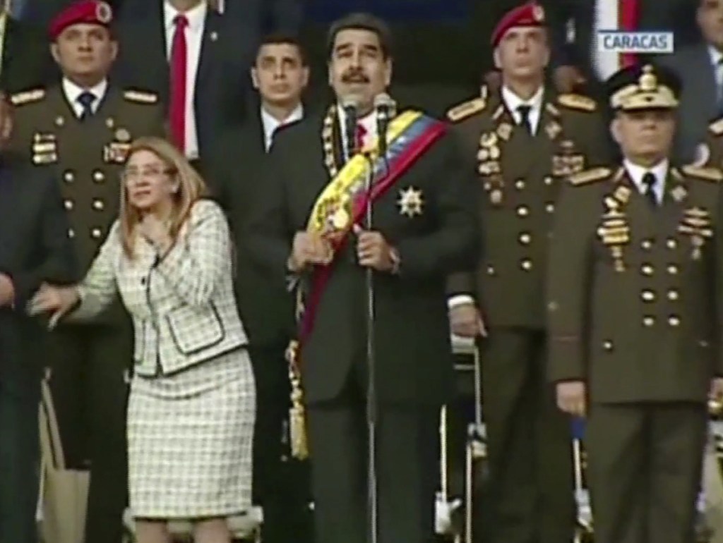 In this still from a video provided by Venezolana de Television, President Nicolas Maduro, center, delivers his speech as his wife Cilia Flores winces and looks up after being startled by and explosion, in Caracas, Venezuela, Aug. 4. Venezuela's government says several explosions heard at a military event were an attempted attack on Maduro. Information Minister Jorge Rodriguez said in a live broadcast that several drone-like devices with explosives detonated near the president. He said Maduro is safe and unharmed but that seven people were injured.