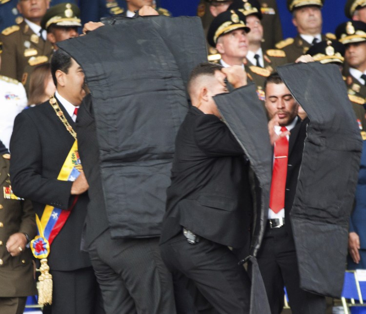 Security personnel try to shield Venezuelan President Nicolás Maduro, at left, on Saturday during an incident involving the detonation of armed drones as he gave a speech in Caracas.