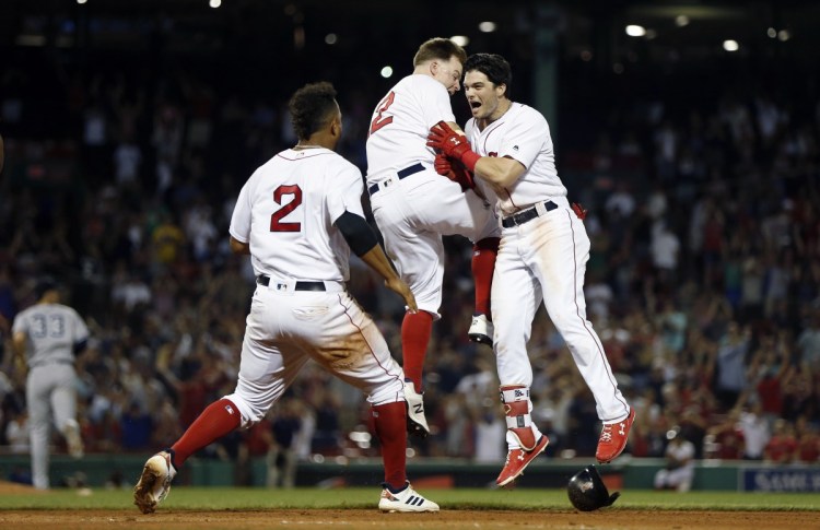 Boston Red Sox's Andrew Benintendi, right, celebrates his winning RBI single with Brock Holt, center, and Xander Bogaerts during the 10th inning Sunday night against the Yankees in Boston.