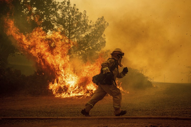A firefighter runs while trying to save a home on July 31 as a wildfire tears through Lakeport, Calif. The residence eventually burned. Authorities say a rapidly expanding Northern California wildfire burning over an area the size of Los Angeles has become the state's largest blaze in recorded history. It's the second year in a row that California has recorded the state's largest wildfire.